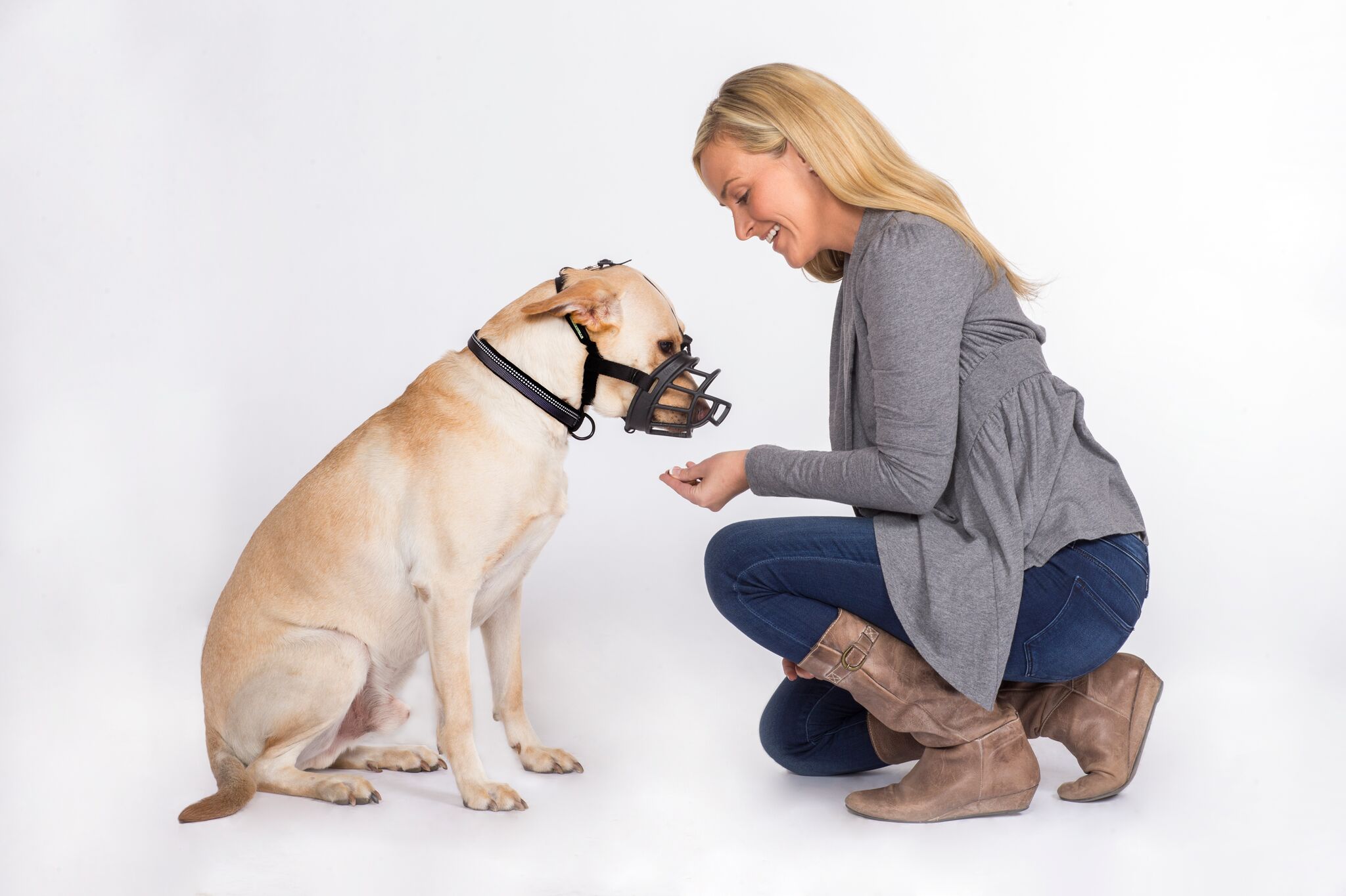 woman feeding a dog a treat while dog wears baskerville ultra muzzle